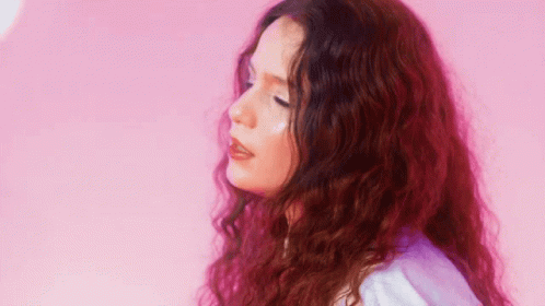 Woman With Long Red Curly Hair In Front Of Pink Wall GIF