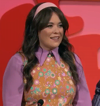 Woman With Microphone Purple Shirt Floral Vest Smiling