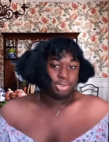 Woman with Necklace and Wig Before Floral Wallpaper