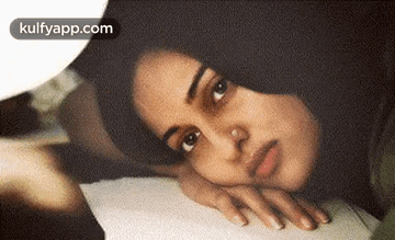 Woman With Nose Ring Lying On Bed Head On Hand GIF