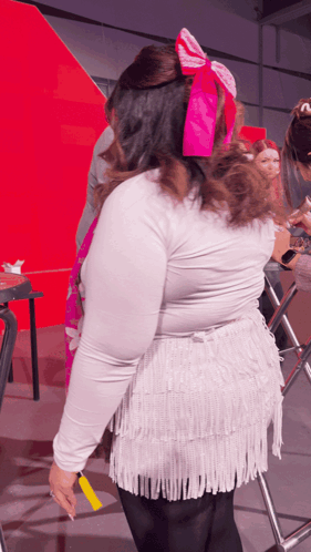 Woman With Pink Bow In Hair In Front Of Red Wall GIF