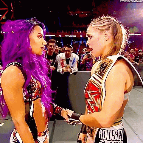Woman With Purple Hair Next To Woman With Rousa Belt GIF