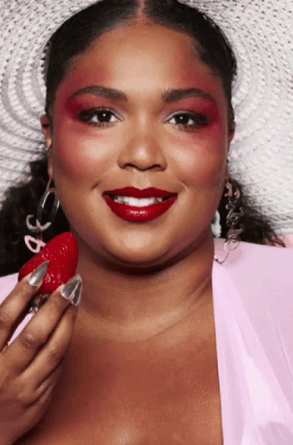 Woman With Red Eyeshadow and Red Lipstick Holding Strawberry