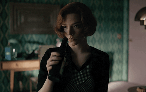 Woman With Red Hair Holding Bottle In Dark Room GIF