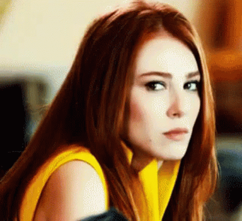 Woman With Red Hair In Yellow Sweater Looking At Camera GIF