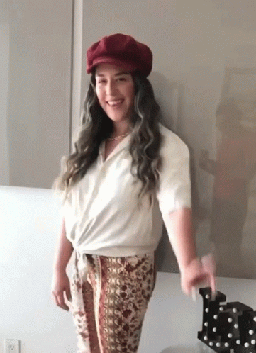 Woman With Red Hat And White Shirt Standing By Wall GIF