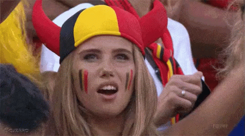 Woman With Red Yellow Black Horned Hat And Painted Faces GIF