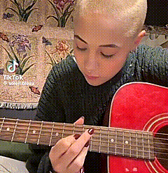 Woman With Shaved Head Playing Red Guitar Eyes Closed