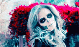 Woman With Skeleton Makeup Sitting in Front of Flowers