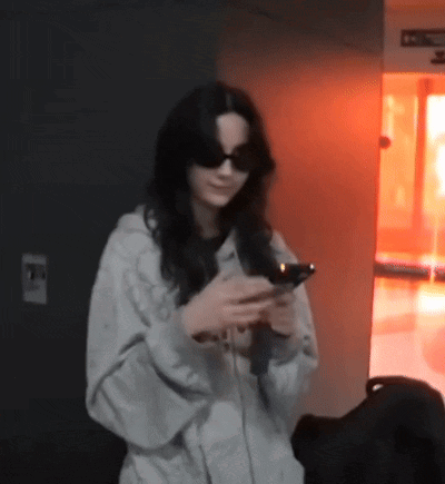 Woman With Sunglasses Looking at Phone in Dark Room