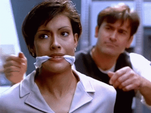 Woman With Tie Around Mouth Looking At Camera GIF
