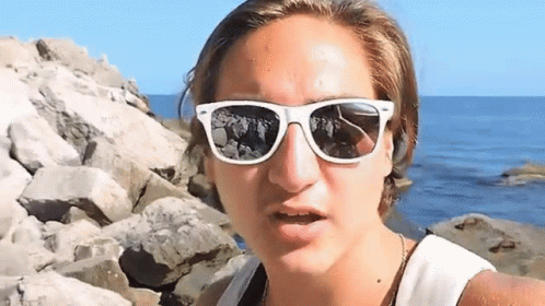 Woman With White Sunglasses On Rocky Shoreline GIF