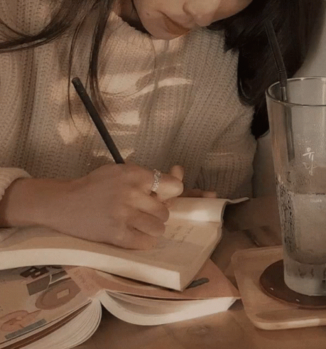 Woman Writing in Notebook Next to Water Glass