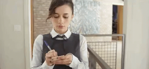 Woman Writing on Paper While Looking at Phone