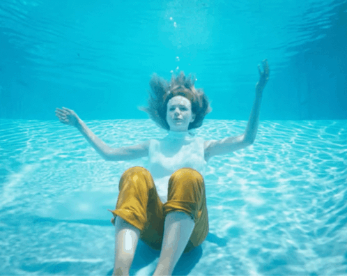 Woman Yellow Pants Underwater Arms Outstretched