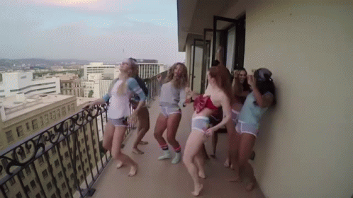 Women Dancing On Balcony Overlooking City GIF