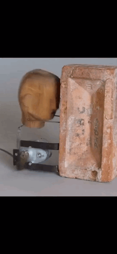 Wooden Head Next To Brick Number 3 GIF