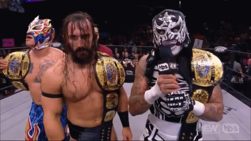 Wrestler in Mask Holding Microphone With Two Wrestlers