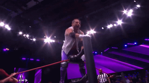 Wrestler in White Vest and Purple Shorts Arms Outstretched