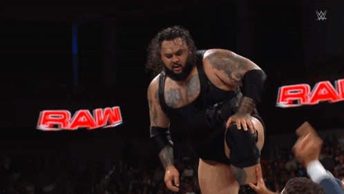 Wrestler Jumping in Front of Crowd With Raw Sign