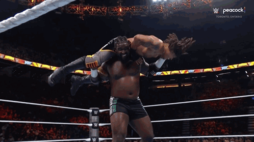 Wrestler Lifted by Another as Referee Watches