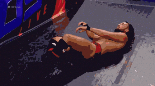 Wrestler Lying On Floor In Front Of 205 Live Wall GIF