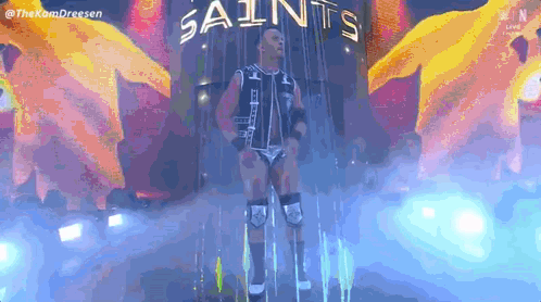 Wrestler Standing In Front Of Saints Sign GIF