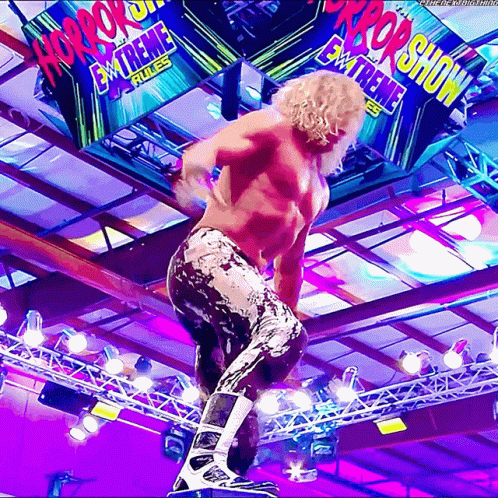 Wrestler Standing on Rope in Front of Horror Show Sign