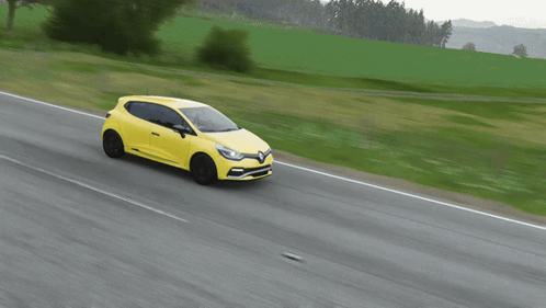 Yellow Car Driving on Road With Grassy Field