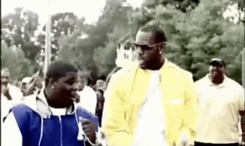 Yellow Jacket Man Talking to Blue Jacket Man in Crowd