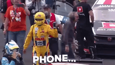 Yellow Racing Suit Man Holding Phone In Front Of Car GIF