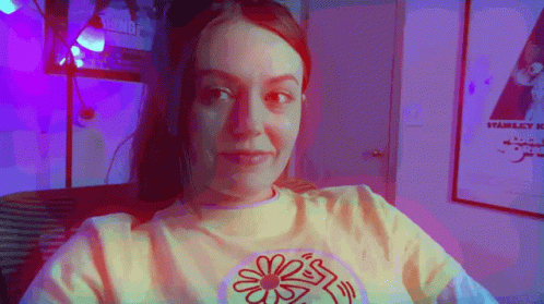 Yellow Shirt Woman With Flower Looking At Camera GIF