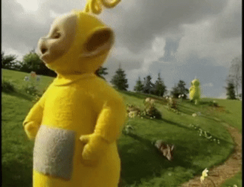 Yellow Teddy Bear Standing On Grass Hill GIF