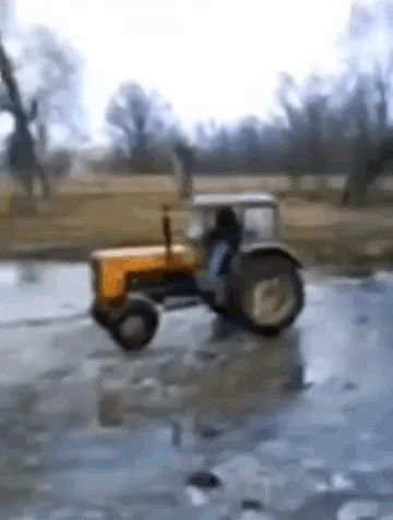 Yellow Tractor Driving Through Icy Puddle