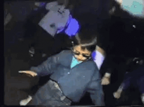 Young Boy Dancing in Dark Room With Crowd