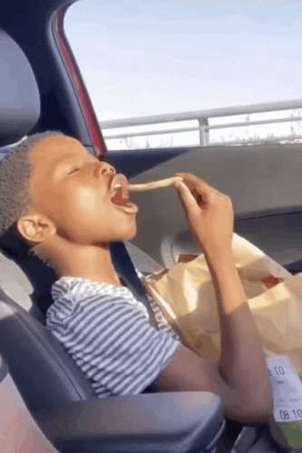 Young Boy Eating French Fries from Bag in Car