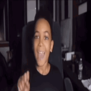 Young Boy in Black Shirt Sitting With Tongue Out