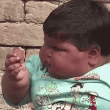 Young Boy in Blue Cartoon Shirt Eating Food