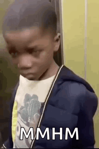Young Boy In Blue Jacket And White Shirt In Front Of Yellow Wall GIF