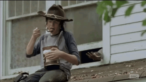 Young Boy in Cowboy Hat Eating on Roof