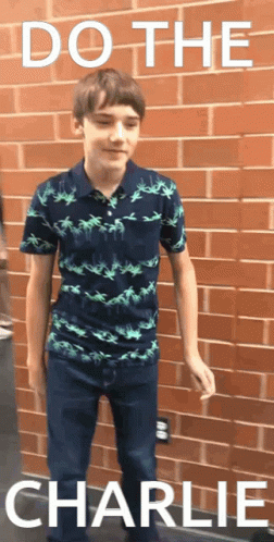Young Boy in Front of Brick Wall With Words Do the Charlie