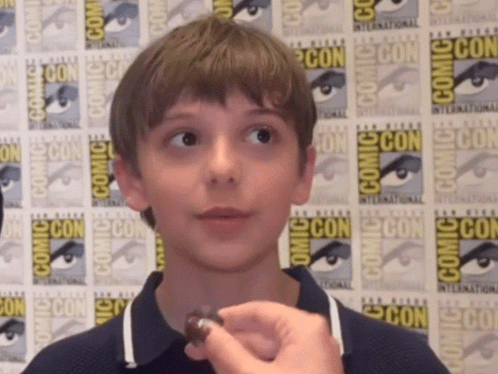 Young Boy In Front Of Comic Con Poster GIF