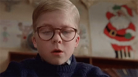 Young Boy in Glasses and Blue Sweater Beside Santa Claus Decoration