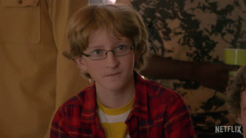 Young Boy In Glasses And Plaid Shirt Sitting At Table GIF
