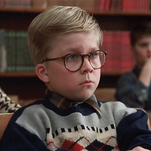 Young Boy in Glasses and Plaid Sweater Sitting in Classroom