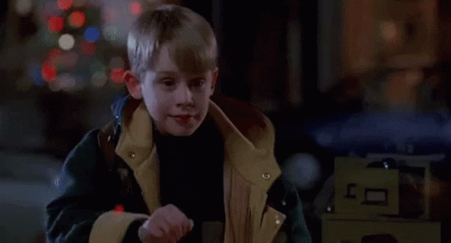 Young Boy in Jacket in Front of Christmas Tree in Dark Room