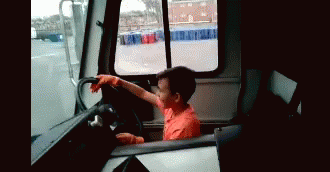 Young Boy in Orange Shirt Driving Truck