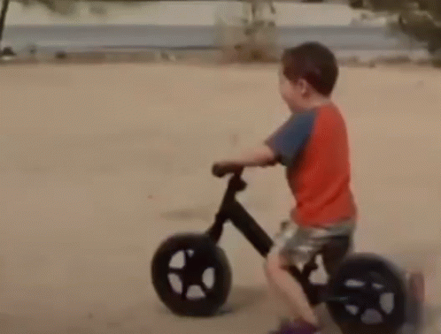 Young Boy in Red Shirt Riding Bike on Dirt Road