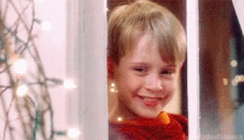 Young Boy in Red Sweater Smiling Out Window