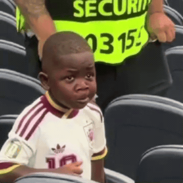 Young Boy in White Adidas Shirt Sitting in Stadium